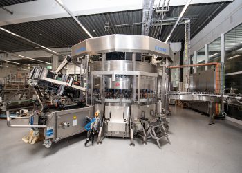 Patentierte Lösung zum Anheften der Folie: Ein Servomotor dreht die Flaschen, Linearmotoren drücken die Folie mithilfe von Schwämmen an die Behälter an. (Bild: Krones)