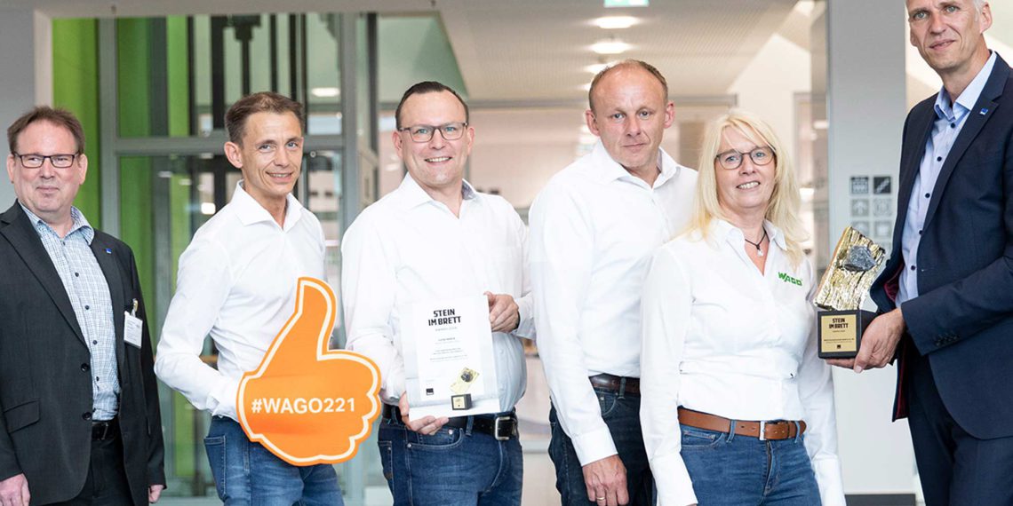 Daumen hoch: Der „Stein im Brett Award“ der ibau GmbH geht in der Kategorie Elektroinstallationstechnik in diesem Jahr an WAGO. Stellvertretend für die gesamte Vertriebsmannschaft nahmen Thorsten Kenter, Oliver Kogel, Stefan Schmitt und Sabine Gißke die Auszeichnung von Ingo Kordowski (links außen) und Guido Schmidt (rechts außen) von ibau entgegen. (Bild: Wago)